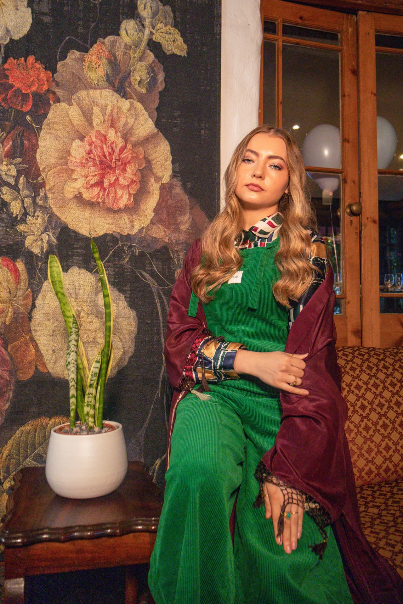 Person wearing forest green PLEBS cotton corduroy dungarees with a patterned shirt and maroon shawl.